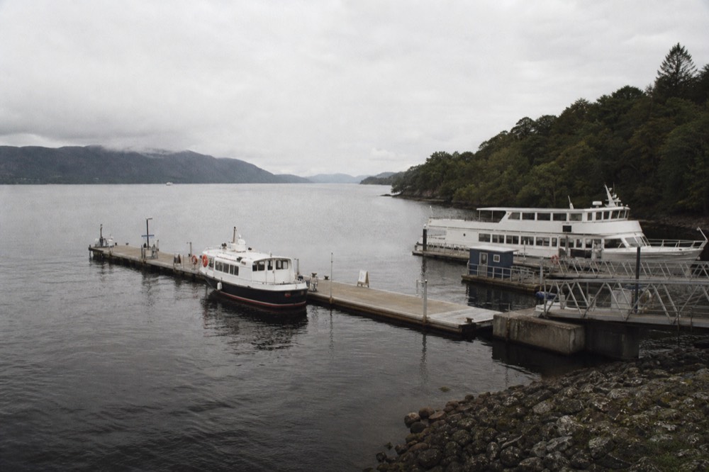 A boarding jetty on Loch Ness with a cruise boat waiting and the dark water and hills of the Great Glen behind